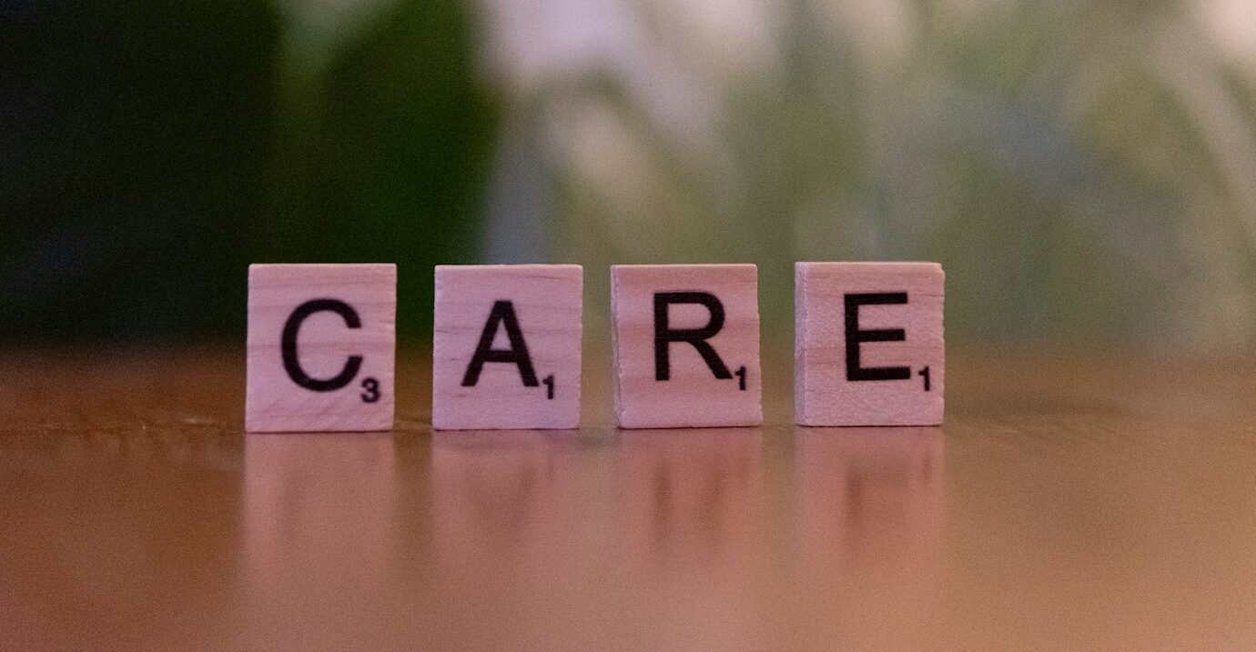 A wooden block spelling care on a table